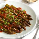 stir fried asparagus covered in red sauce