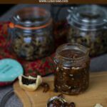 a spoonful of homemade mincemeat on wooden board with jars in the background