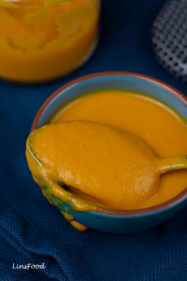 teaspoon filled with aji amarillo paste resting on a small blue bowl