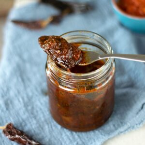 homemade chipotles in adobo on a fork resting on glass jar