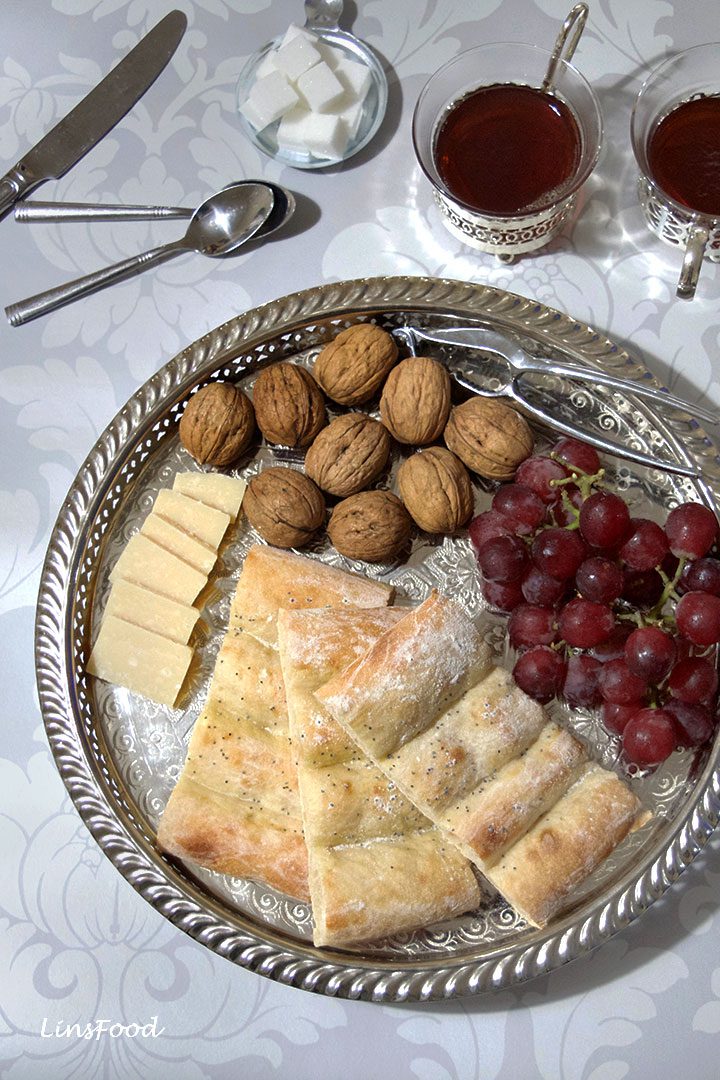 Slices of Barbari on silver tray with walnuts, cheese and grapes
