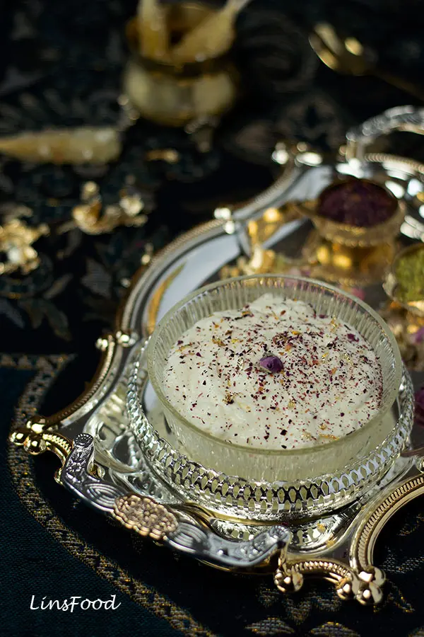 ashta cream in a glass container topped with crushed rose petals
