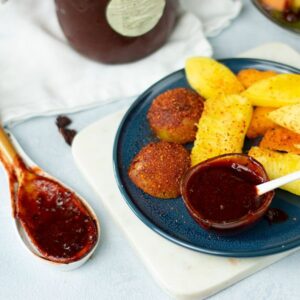 chamoy recipe in a small glass bowl and wooden spoon with cut fruit