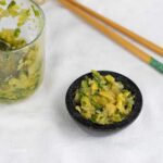 ginger and spring onion sambal in a tiny black bowl and glass jar with chopsticks