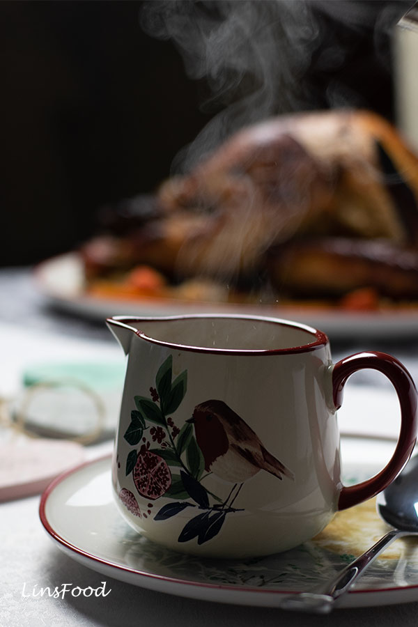 Steam rising from a Christmas gravy jug with a roast turkey in the background