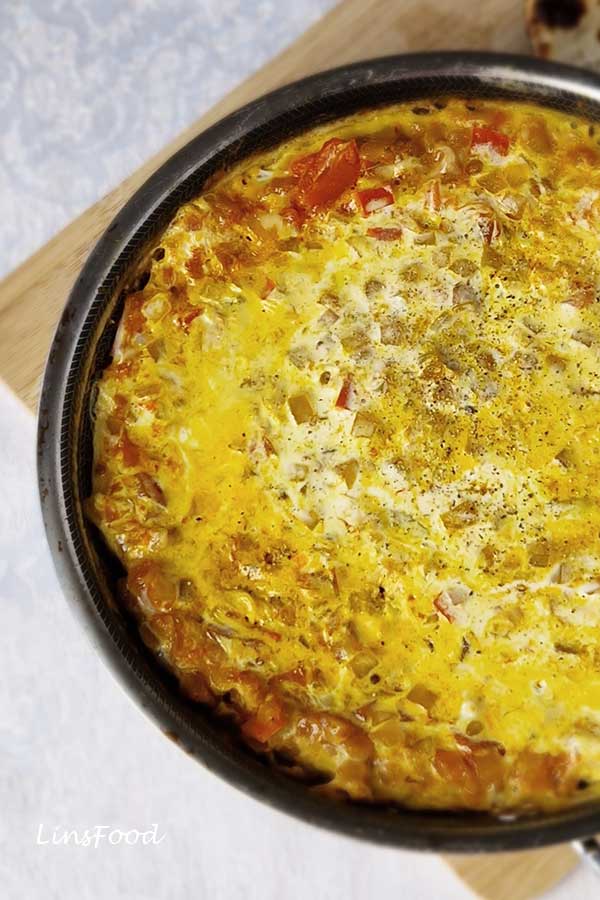Close-up of Yemeni lahsa with soft eggs, tomatoes and creamy cheese cooked in a small pan.
