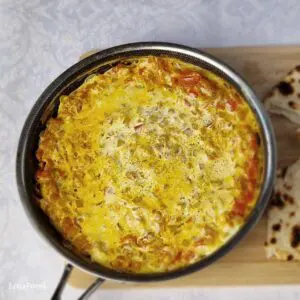 Yemeni lahsa with creamy eggs, tomatoes and cheese served in a pan with flatbread.