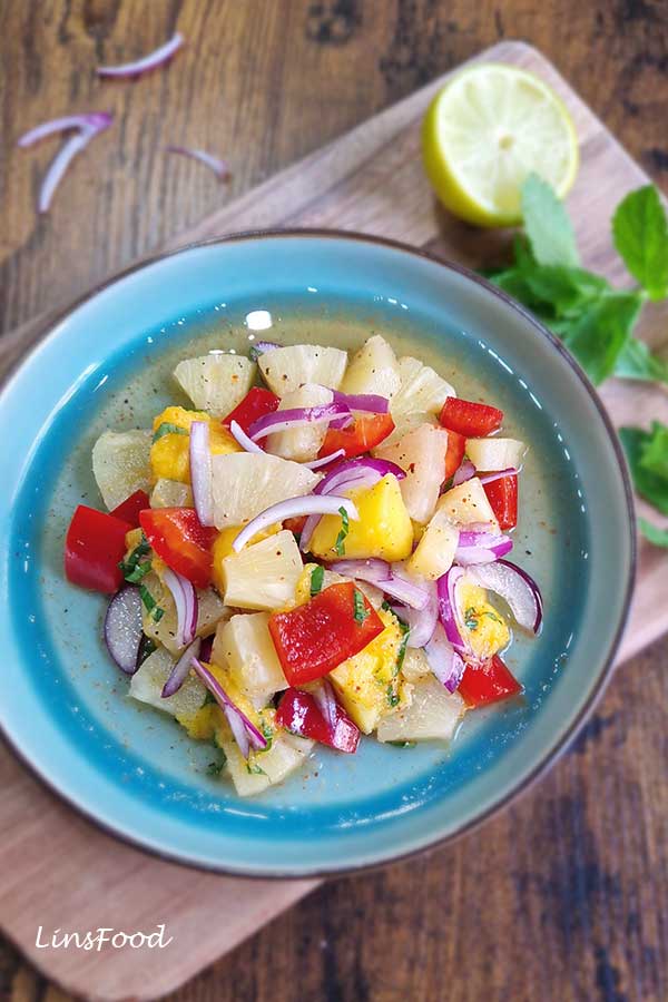 ineapple mango salad with mint, lime, red pepper and red onion in a blue bowl.