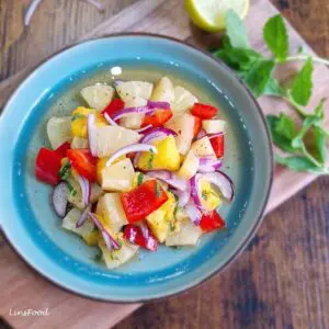 Tropical pineapple mango salad with red pepper, red onion and mint in a blue serving bowl.