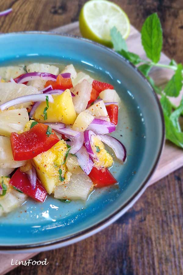 Close-up of pineapple and mango salad with lime dressing, red pepper, red onion and chopped mint.