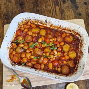 Vegan fasolia traybake with butter beans, potatoes, cherry tomatoes and parsley in a tomato olive oil sauce.