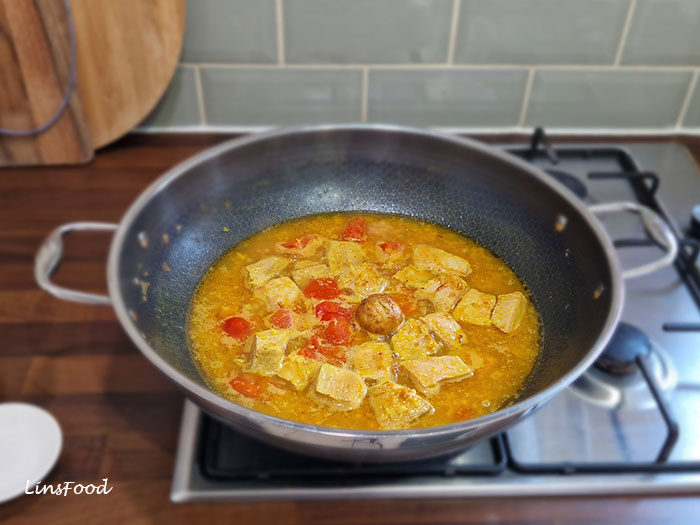 Omani paplou simmering in a wide pan with chunks of tuna, softened tomatoes and a whole brown dried lime, or limoo, in the centre.