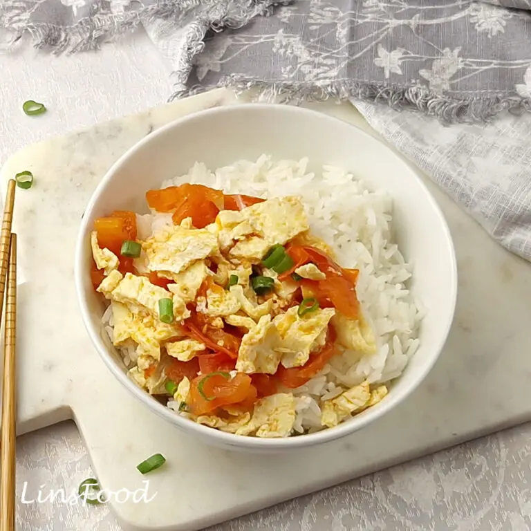 Bowl of Chinese tomato egg stir-fry with steamed rice, tomatoes, soft eggs and spring onions