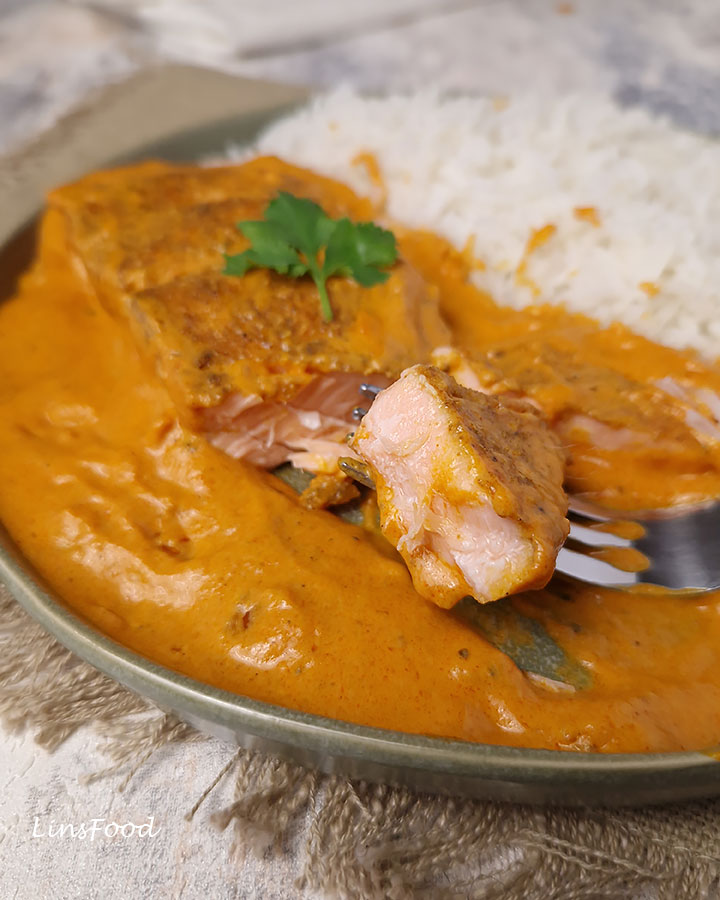 piece of creamy masala salmon on a fork next to white rice