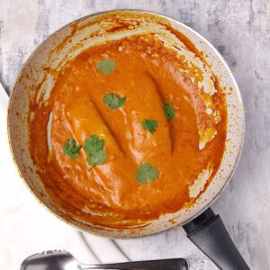 2 salmon fillets covered in creamy masala curry in a white single handed wok