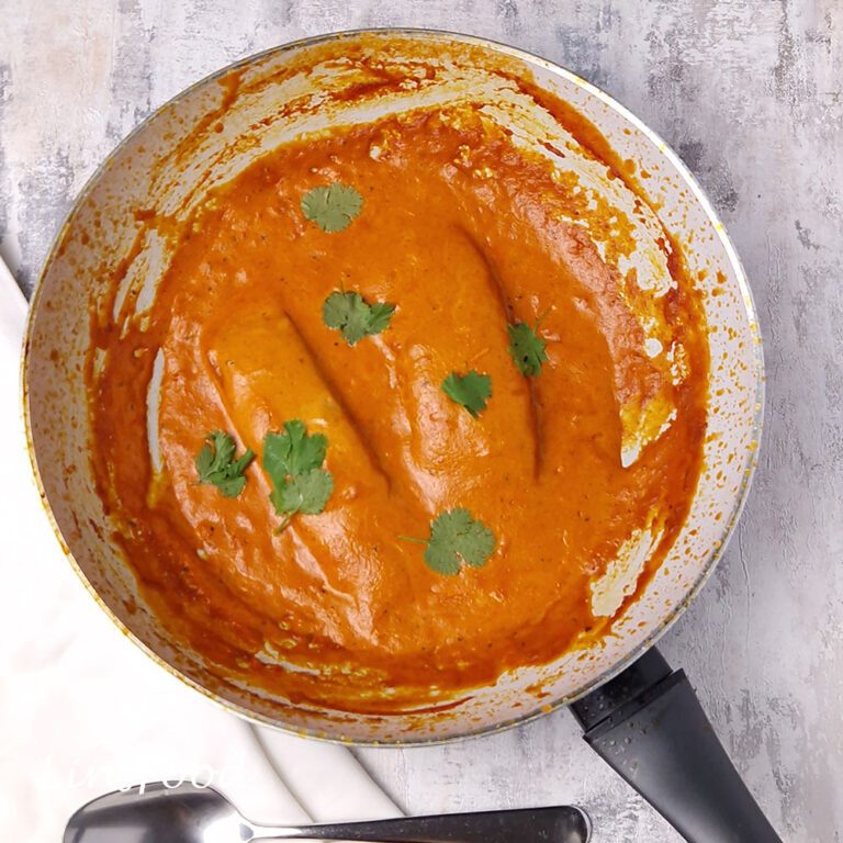 2 salmon fillets covered in creamy masala curry in a white single handed wok