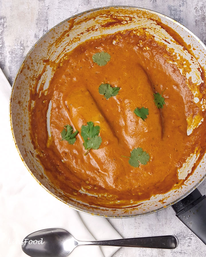 2 salmon fillets covered in creamy masala curry in a white single handed wok